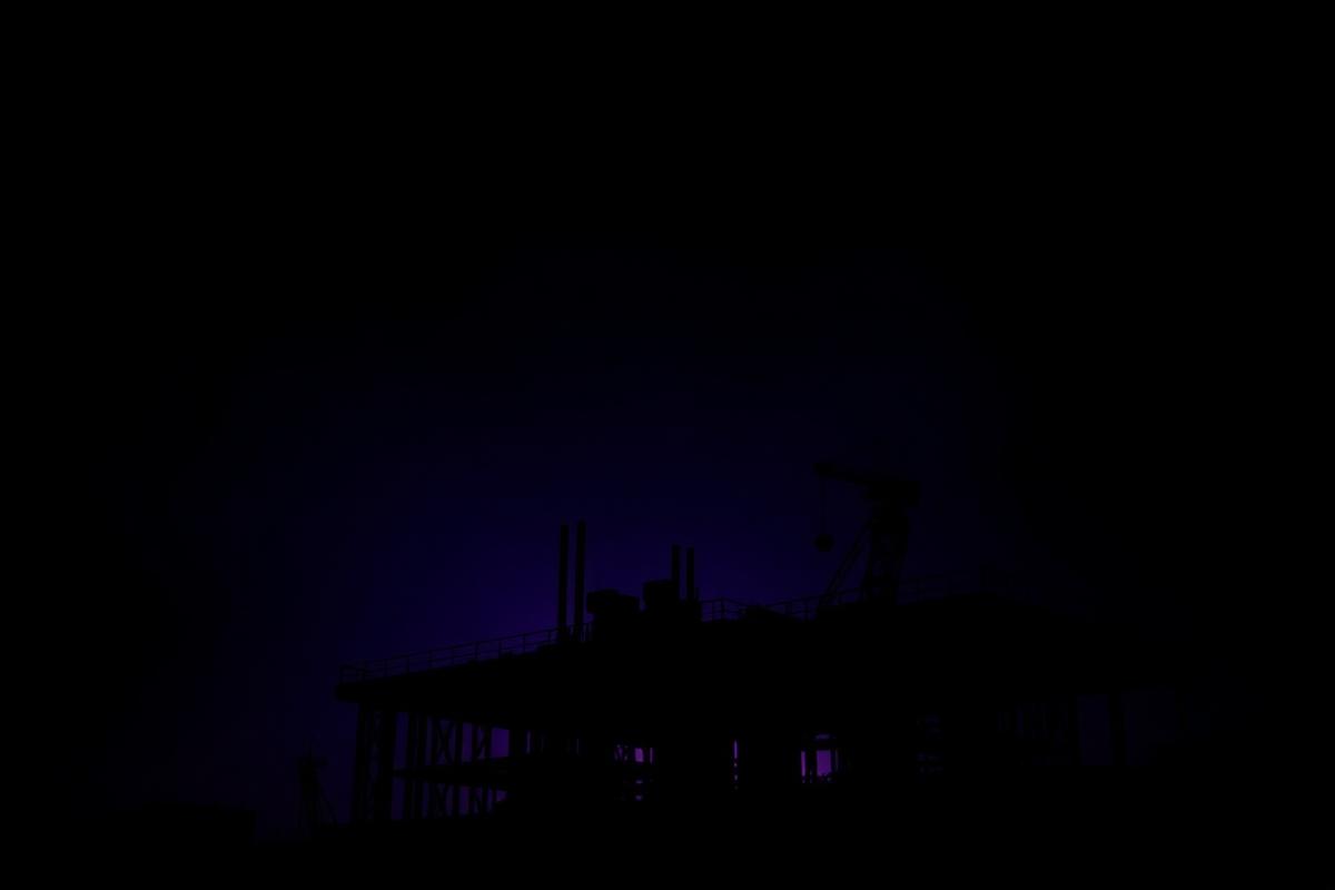 Steel structure of a construction site at night lit by violet light